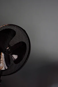 Close-up of a professional repairing a wall-mounted air circulator.