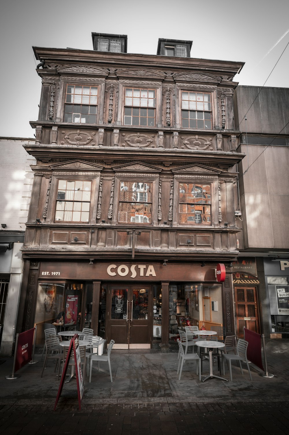 an old building with tables and chairs outside of it