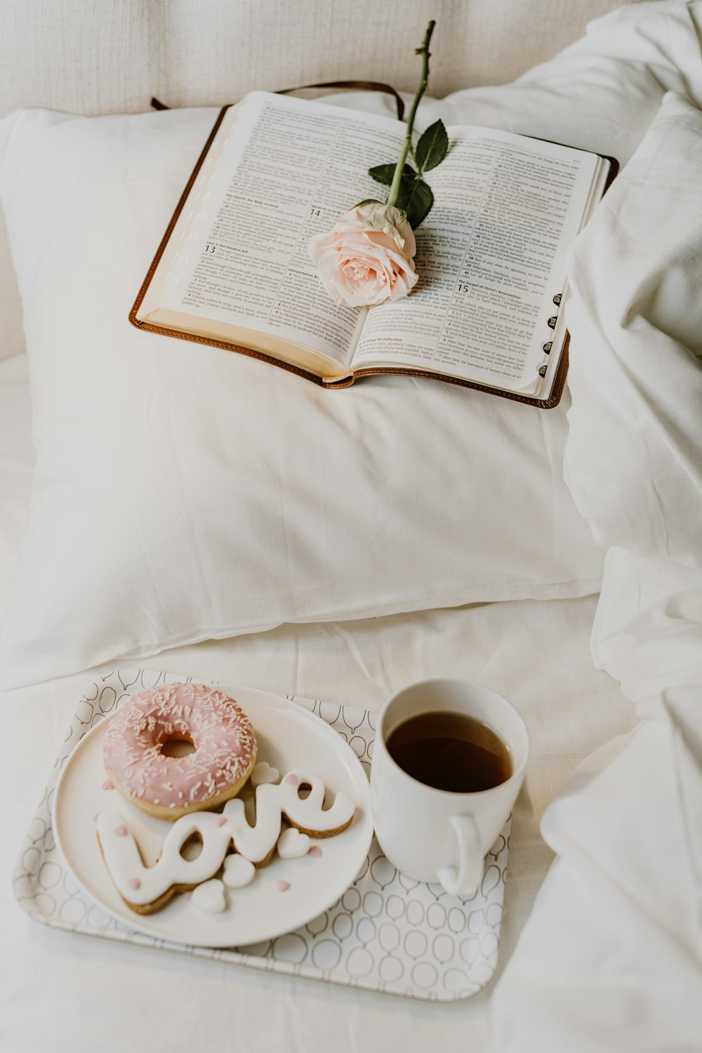 a cup of coffee and a donut on a bed