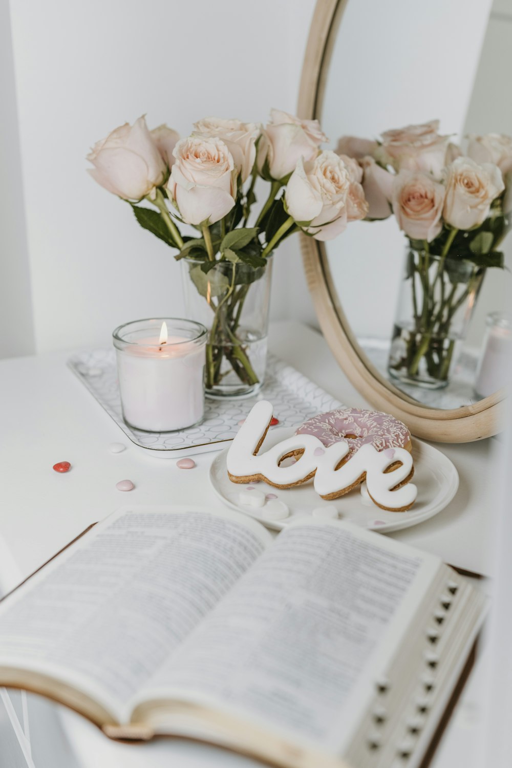 a white table topped with a book and a vase filled with flowers