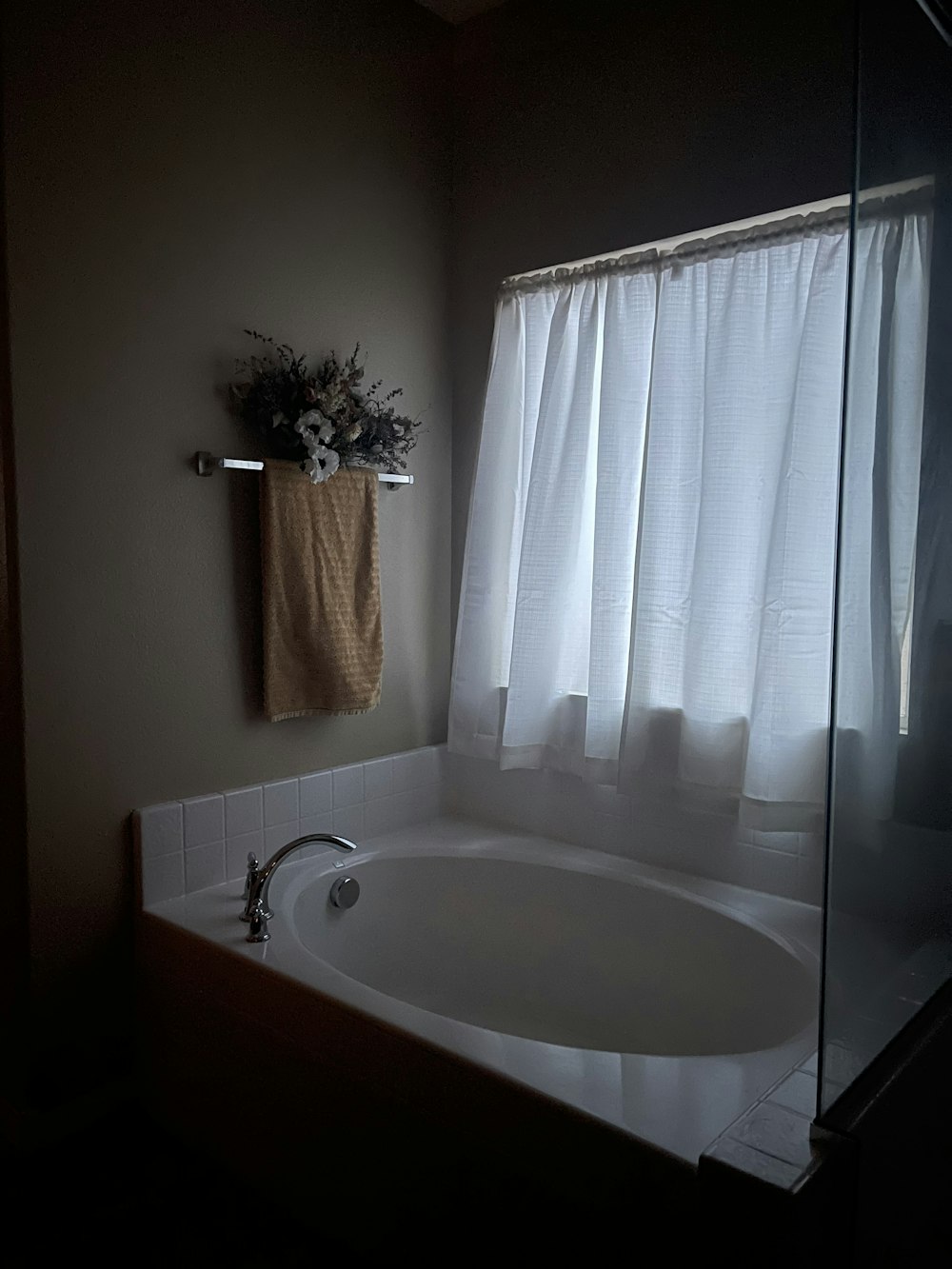 a bath tub sitting under a window next to a towel rack