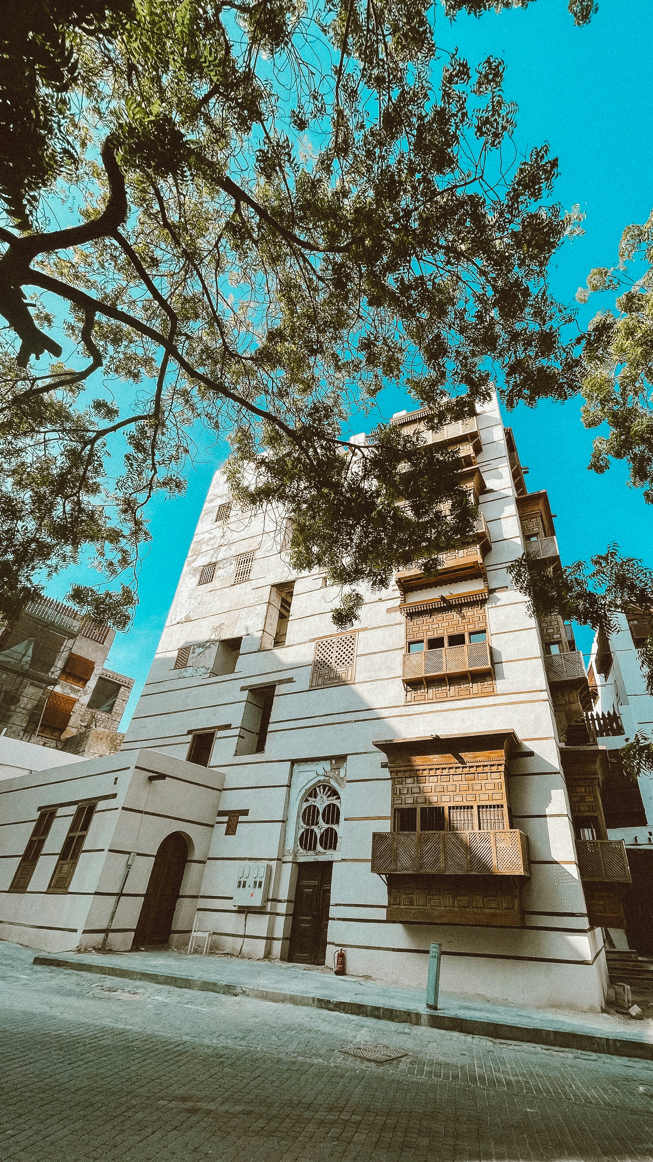 a tall white building sitting next to a tree