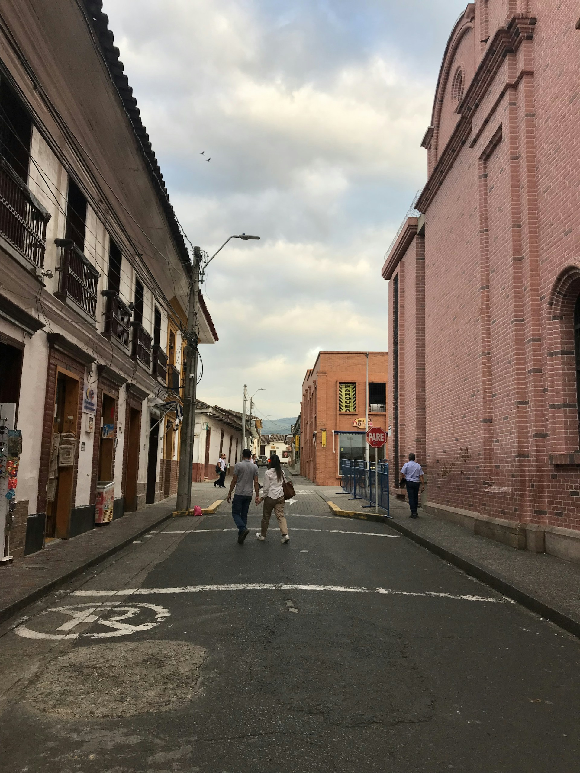 a group of people walking down a street next to tall buildings
