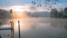 Sunrise over the serene Pokhara lake with mountains in the background.