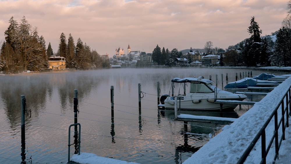 a row of boats sitting on top of a lake covered in snow