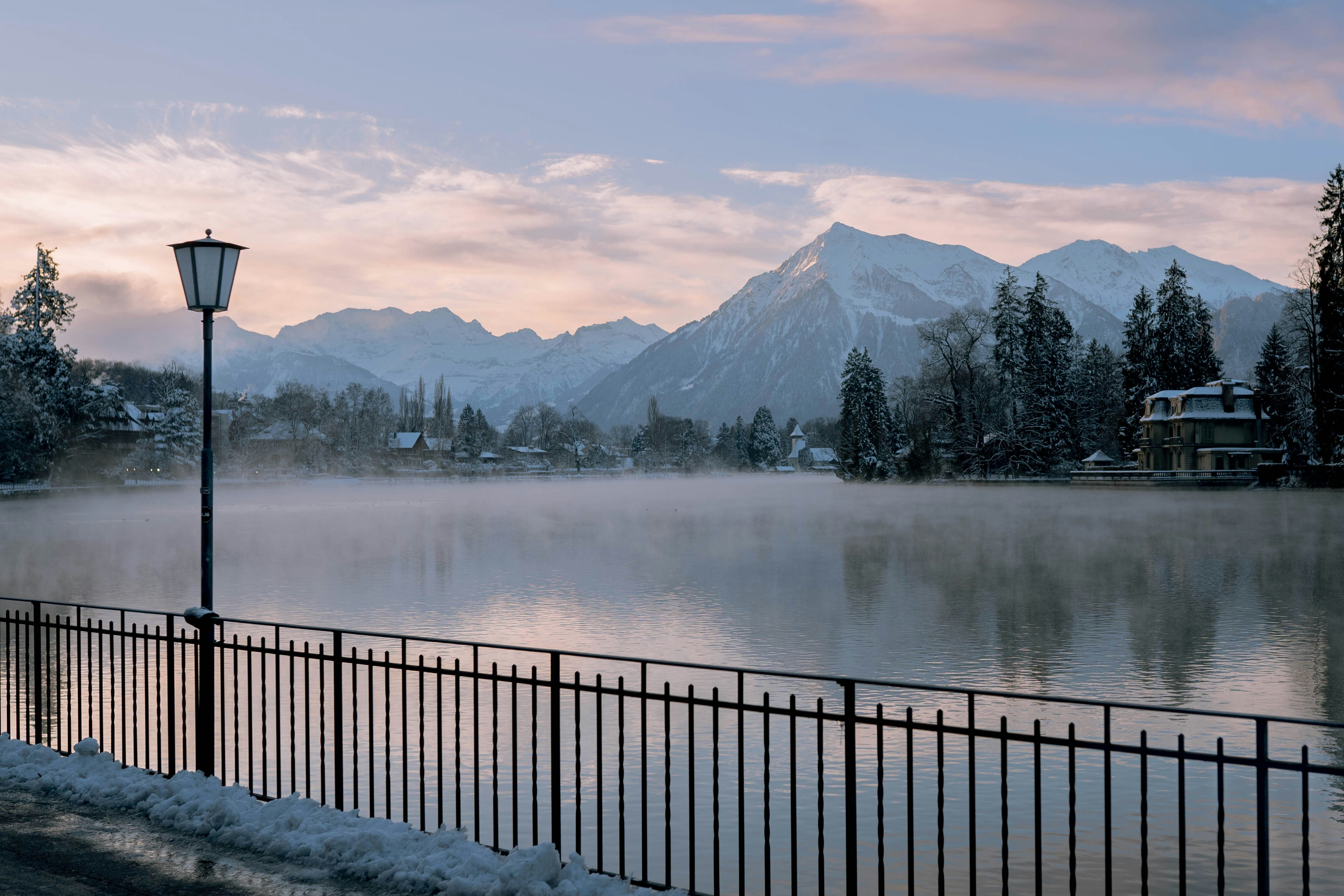 a lake with mountains in the background and a lamp post in the foreground