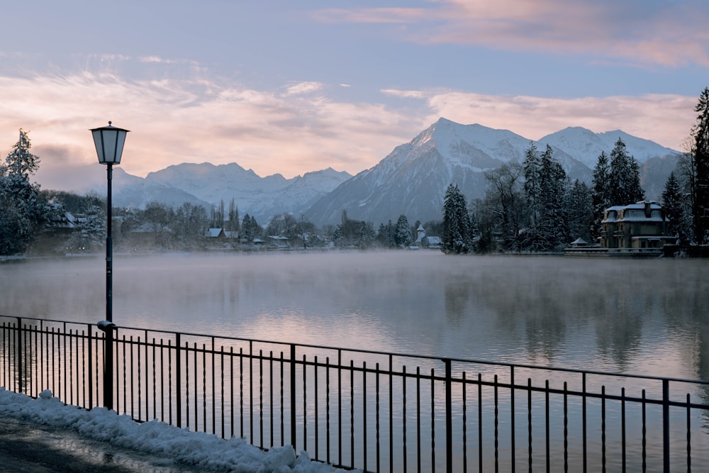 a lake with mountains in the background and a lamp post in the foreground