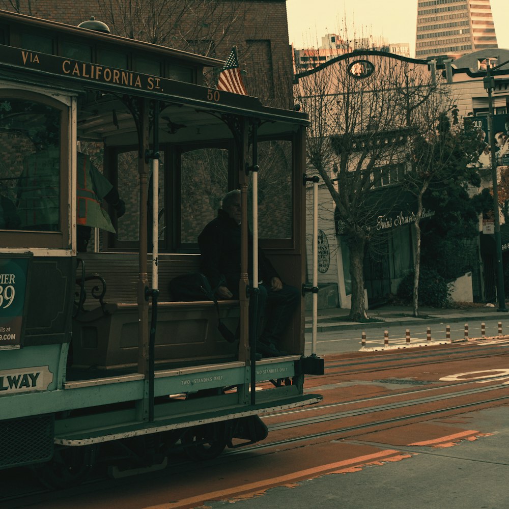 a trolley car traveling down a street next to a tall building