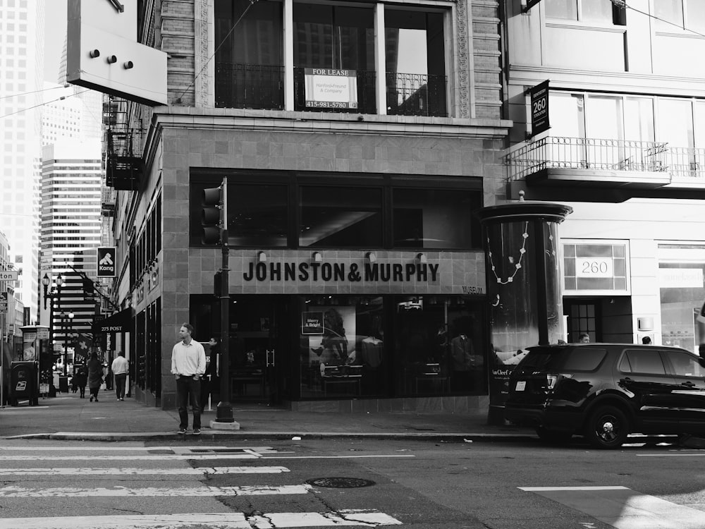 a black and white photo of a man standing in front of a store