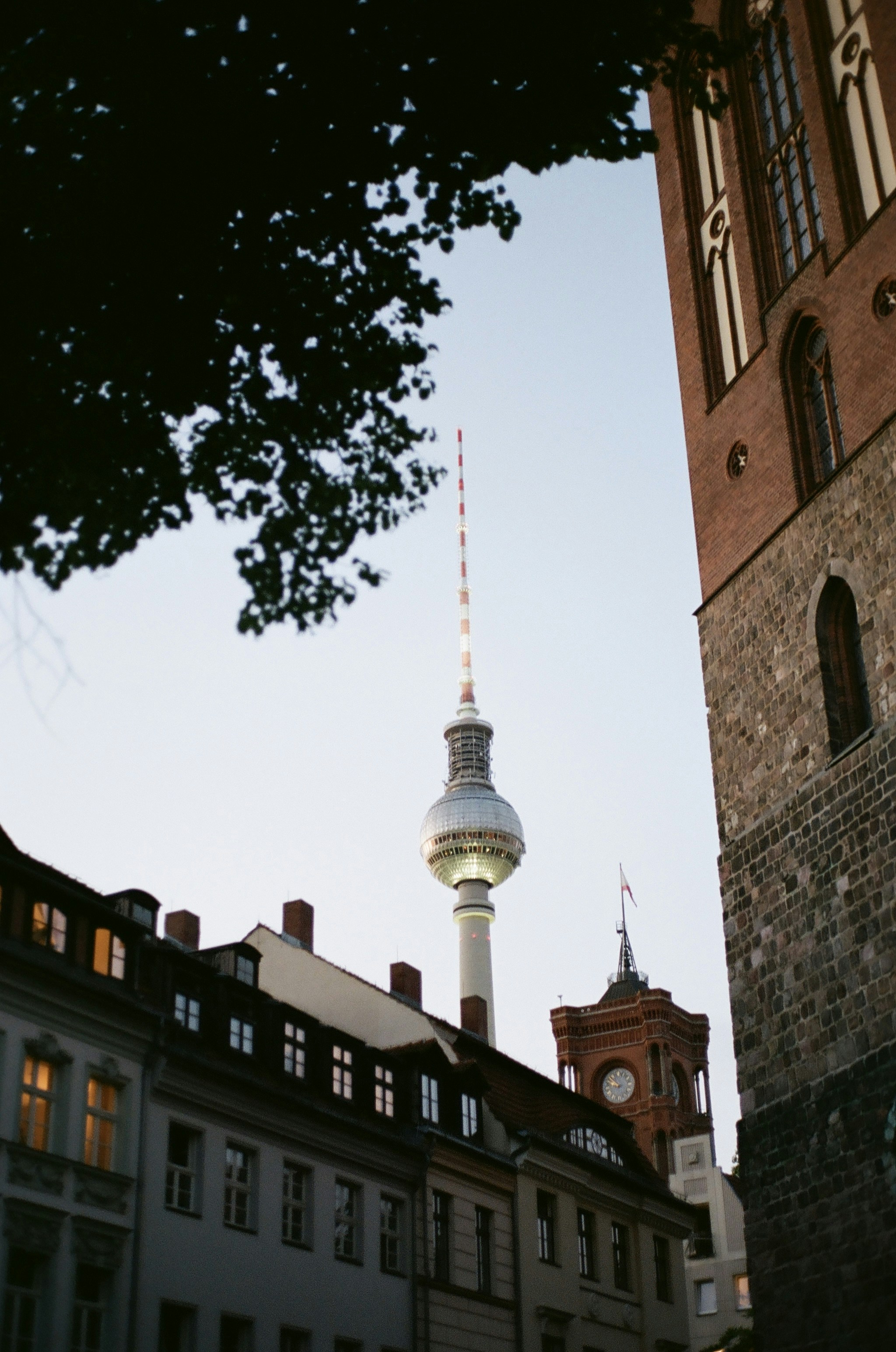 Berlin TV tower framed by old buildings at dusk.