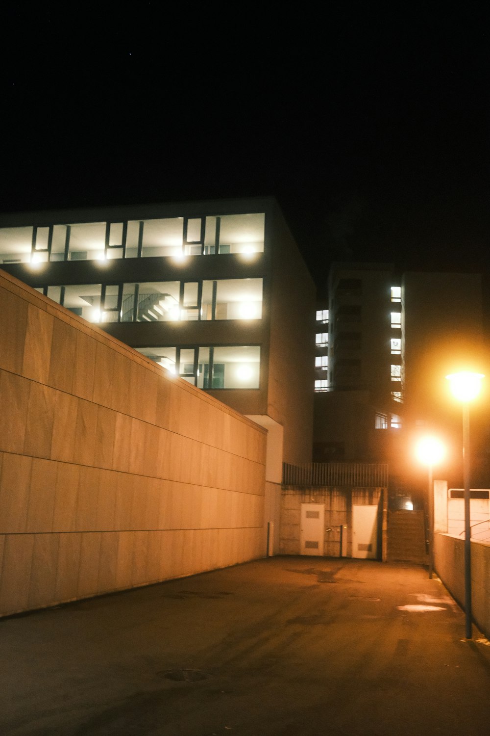 an empty parking lot in front of a building at night