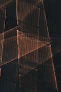 The image contains overlapping geometric shapes and lines creating an abstract pattern with a textured appearance. The lighting and shadows produce a layered effect.