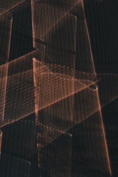 The image contains overlapping geometric shapes and lines creating an abstract pattern with a textured appearance. The lighting and shadows produce a layered effect.