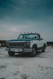 a truck parked on a sandy beach under a cloudy sky