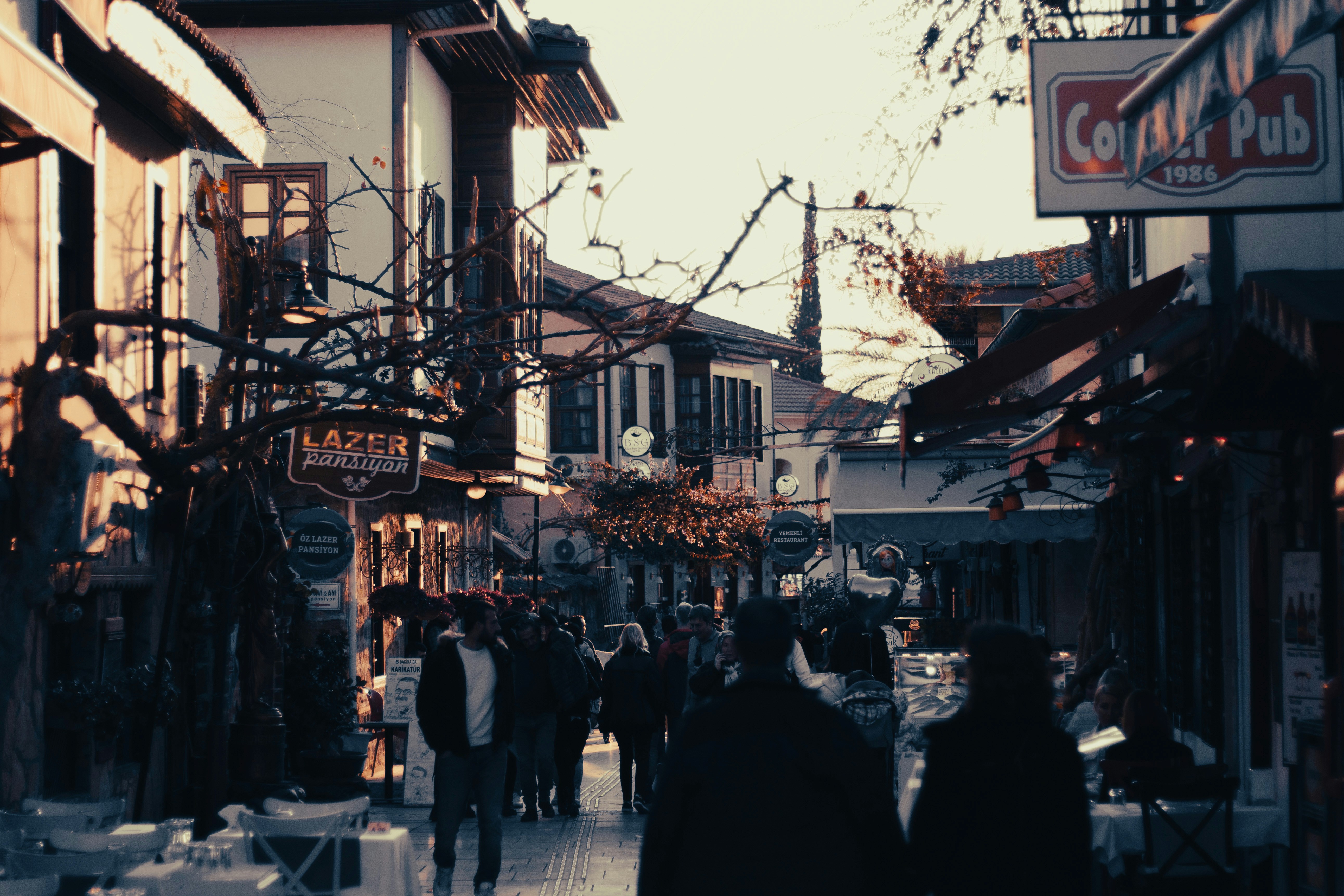 a group of people walking down a street next to tall buildings