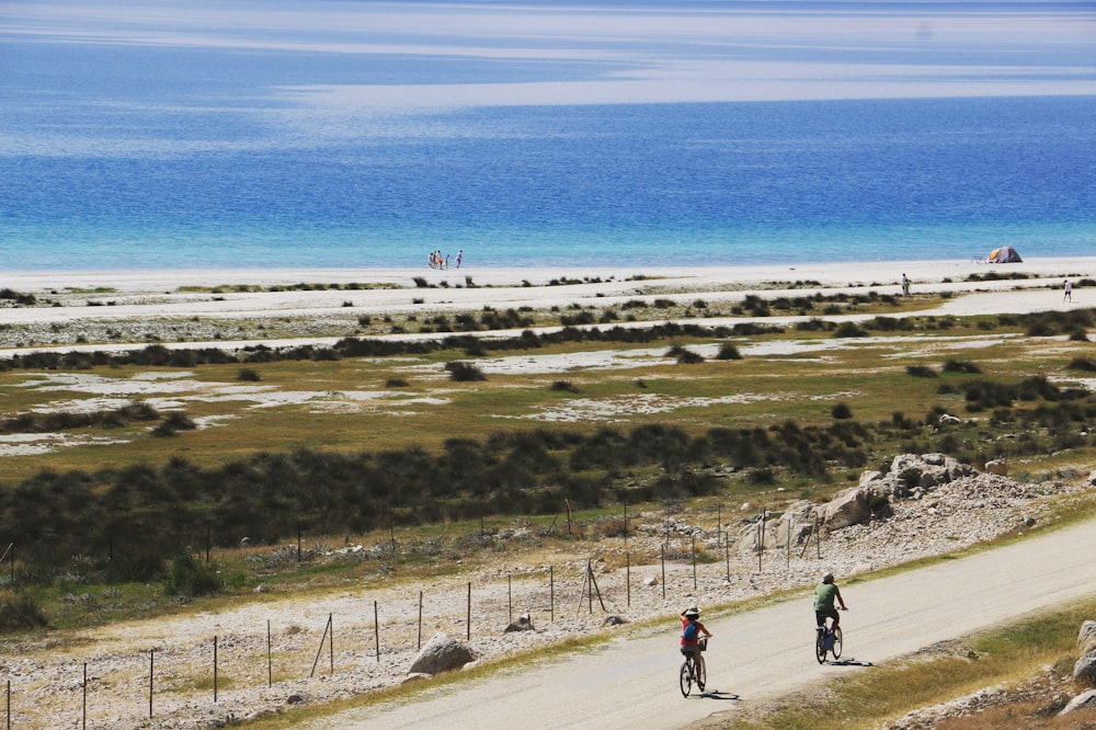 a couple of people riding bikes down a dirt road