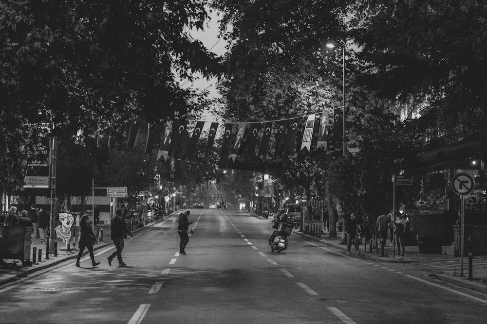 a black and white photo of people walking down a street