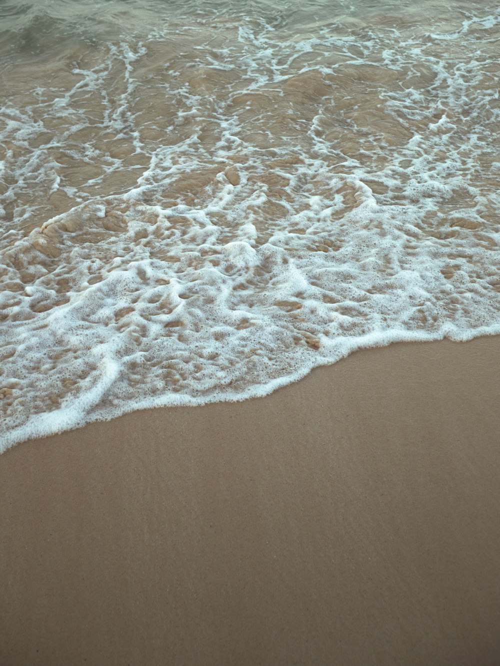 a sandy beach with waves coming in to shore