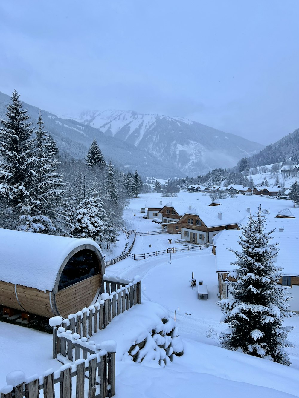 a snow covered landscape with a small cabin in the foreground