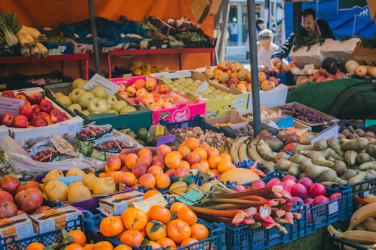 Vibrant crates overflowing with freshly harvested fruits and vegetables at a bustling market stall.