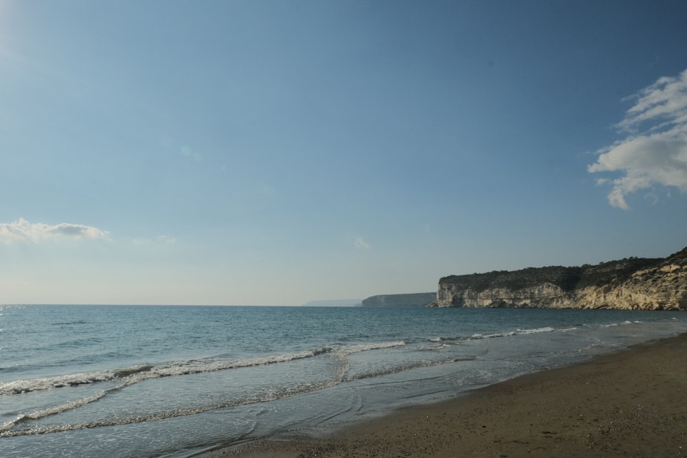 a sandy beach with a cliff in the background