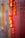 A vibrant display of traditional Chinese decorative firecrackers hangs vertically. The firecrackers are primarily red with intricate gold designs and Chinese characters. These cylindrical decorations are often associated with celebrations and festivities, symbolizing good luck and prosperity. The background is blurred, showcasing a colorful gradient, enhancing the focus on the decorations.