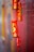 A vibrant display of traditional Chinese decorative firecrackers hangs vertically. The firecrackers are primarily red with intricate gold designs and Chinese characters. These cylindrical decorations are often associated with celebrations and festivities, symbolizing good luck and prosperity. The background is blurred, showcasing a colorful gradient, enhancing the focus on the decorations.
