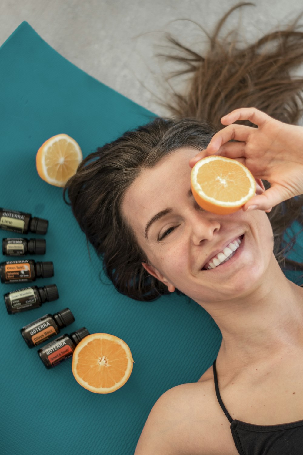a woman laying on a mat with oranges and essential oils