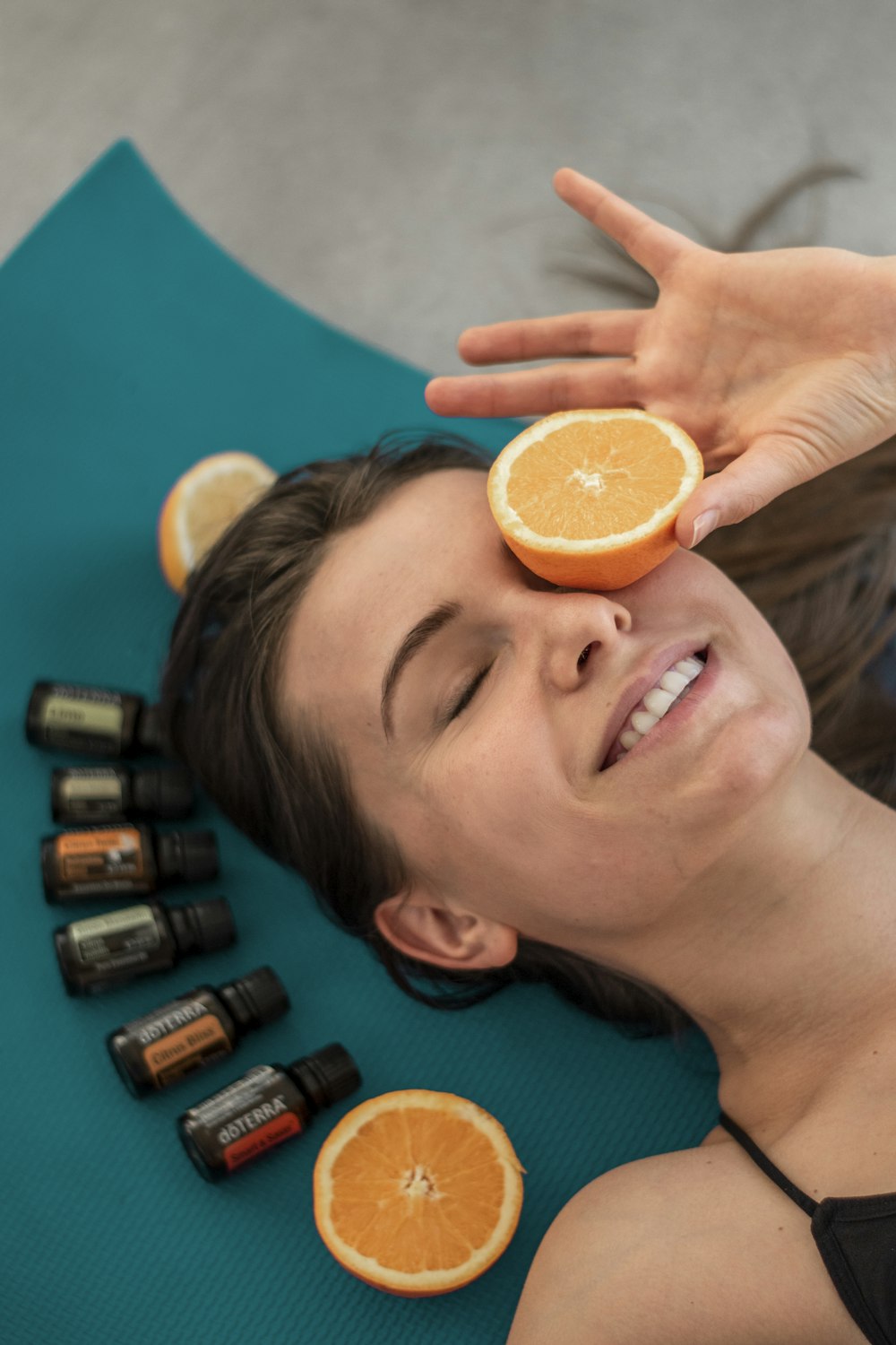 a woman laying on a mat with oranges on her head