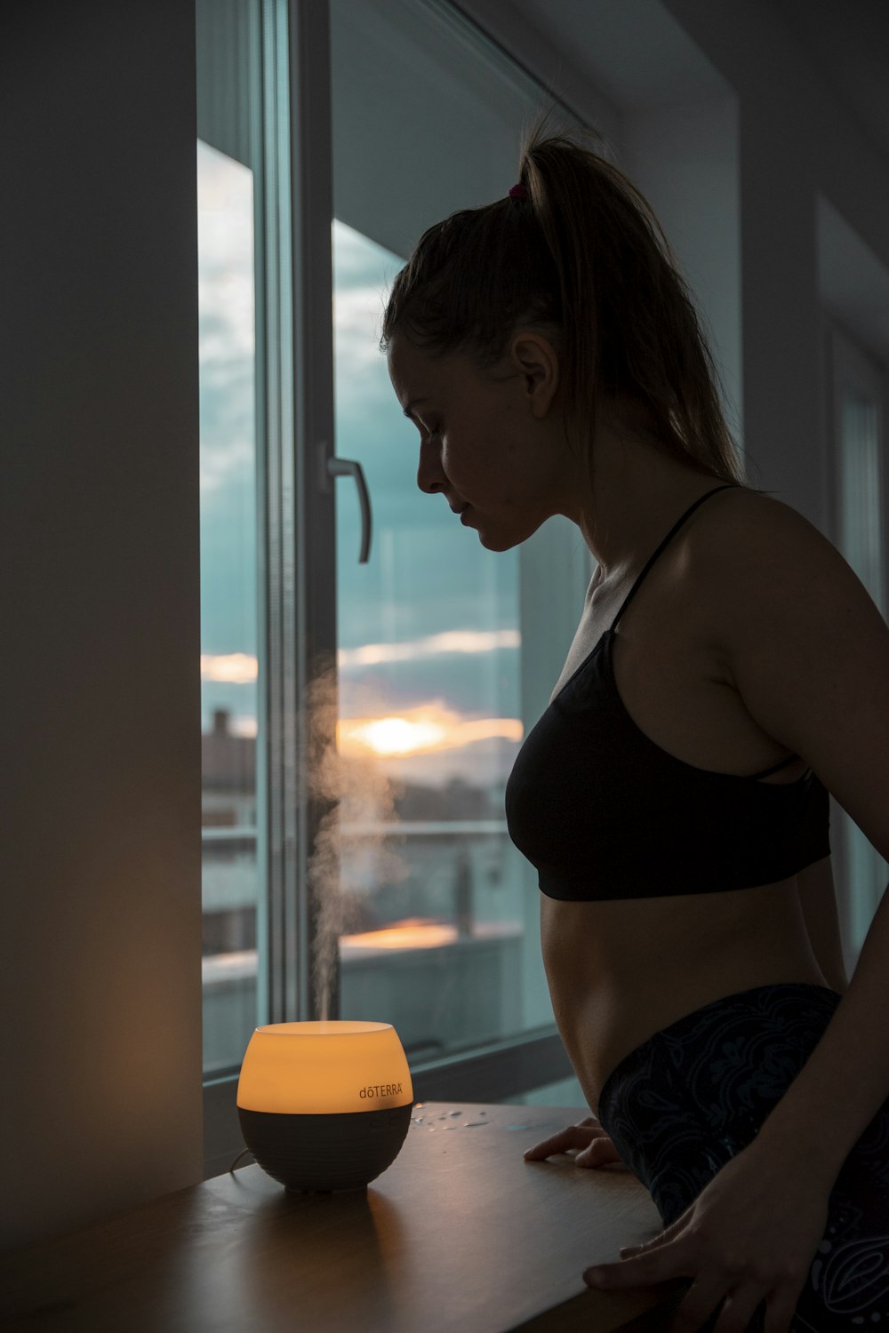 a woman standing in front of a window next to a window sill