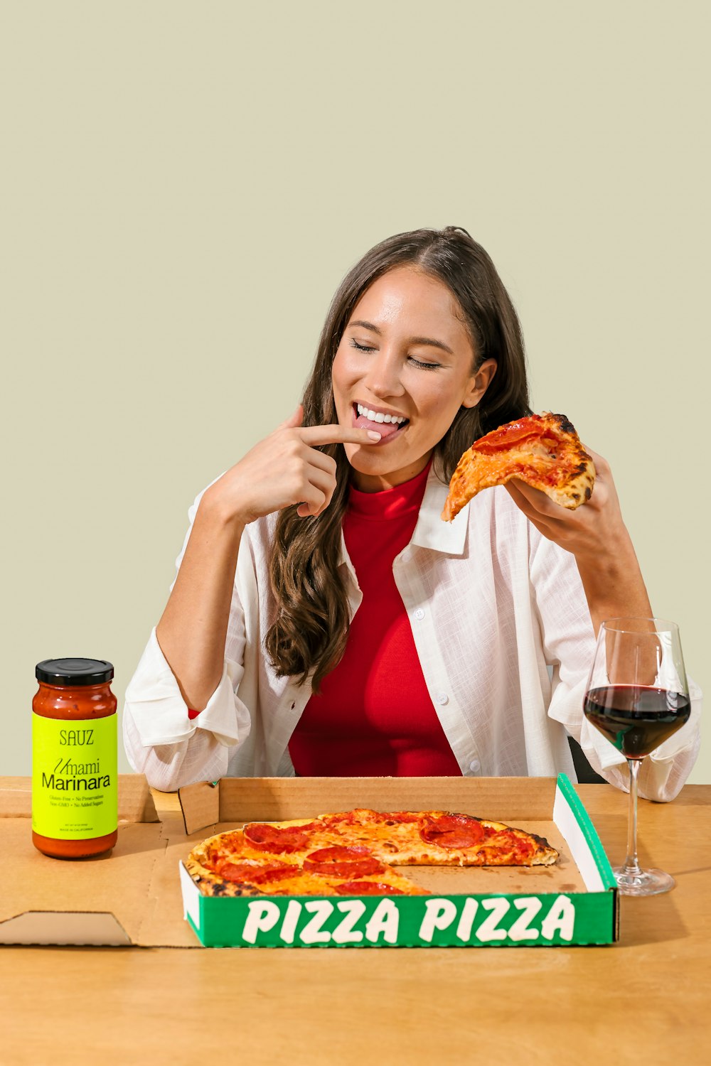 a woman sitting at a table eating a slice of pizza