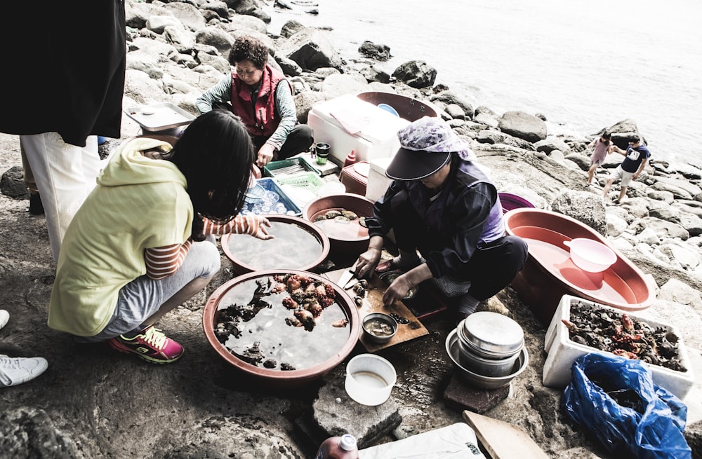 a group of people sitting on top of a rocky beach