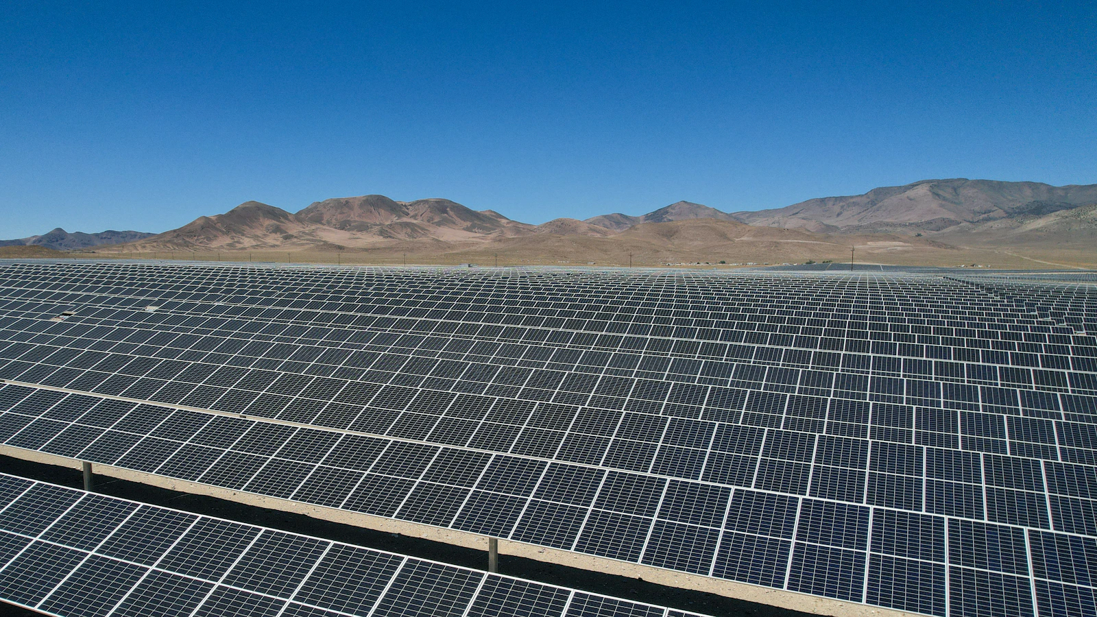 Rows of solar panels stretching across a desert plain