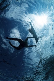 a couple of people swimming in a body of water