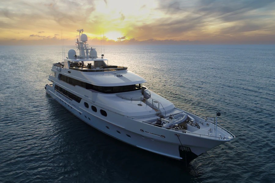 A large motor yacht under way at golden hour, seen from the bow quarter.