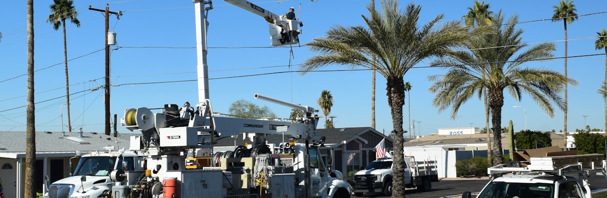 a white utility truck driving down a street next to palm trees