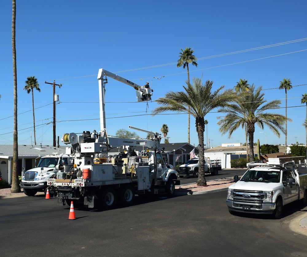 a white utility truck driving down a street next to palm trees