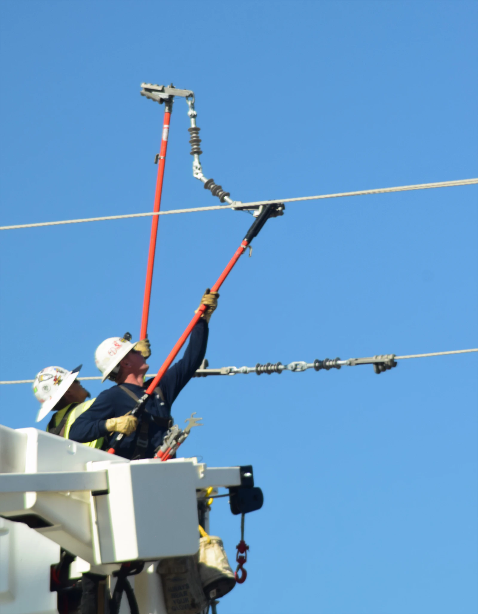Electrician working on overhead power lines from a utility lift