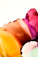 A vibrant, abstract composition with flowing colors blending seamlessly into one another, dominated by shades of orange, pink, and purple. The smooth, organic shapes and translucent layers create a sense of fluidity and movement, resembling watercolor paint or ink dispersing in liquid.