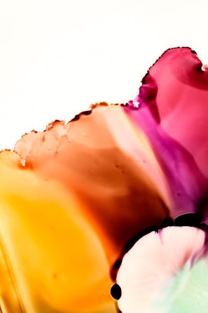A vibrant, abstract composition with flowing colors blending seamlessly into one another, dominated by shades of orange, pink, and purple. The smooth, organic shapes and translucent layers create a sense of fluidity and movement, resembling watercolor paint or ink dispersing in liquid.