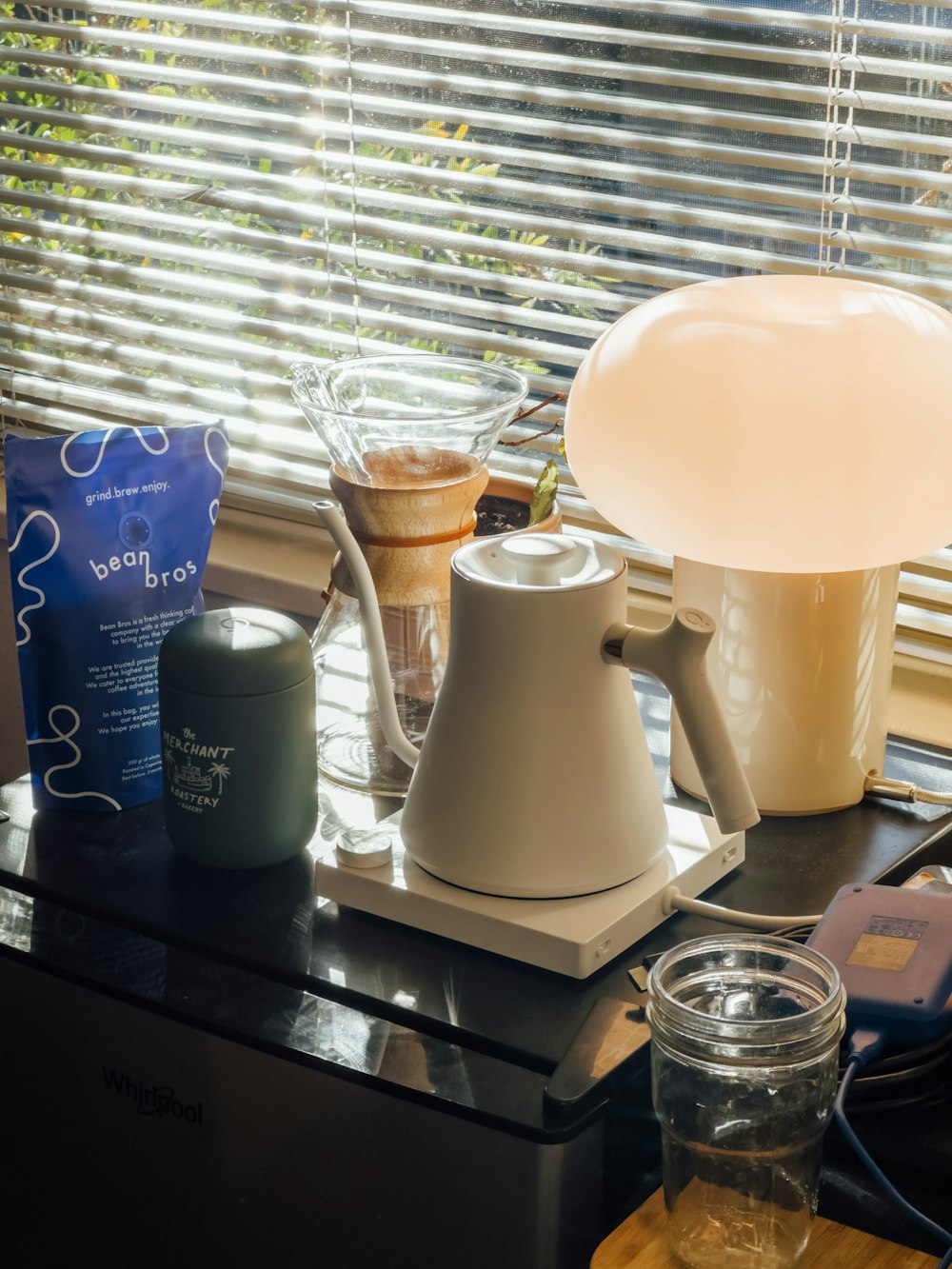 a coffee pot sitting on top of a table next to a lamp