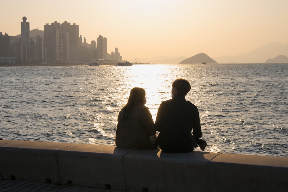 a couple of people sitting on top of a cement wall