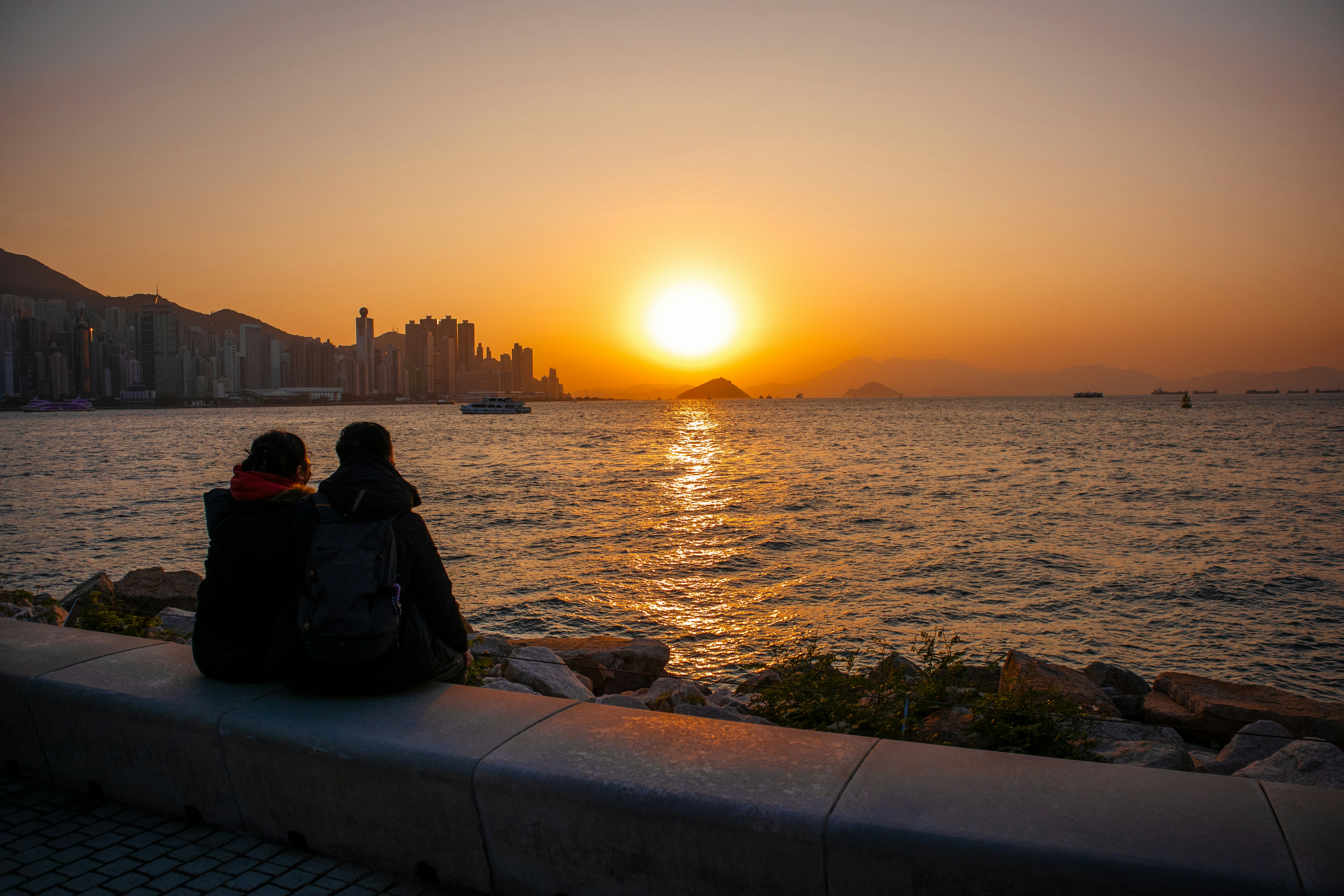 a couple of people sitting on top of a stone wall