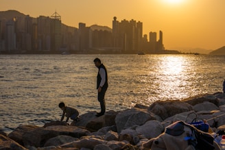 A happy family standing in front of a famous global city skyline, rays of evening light glowing softly.