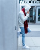 Model leaning against an urban wall wearing a vibrant hooded sweatshirt.