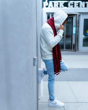 Model leaning against an urban wall wearing a vibrant hooded sweatshirt.