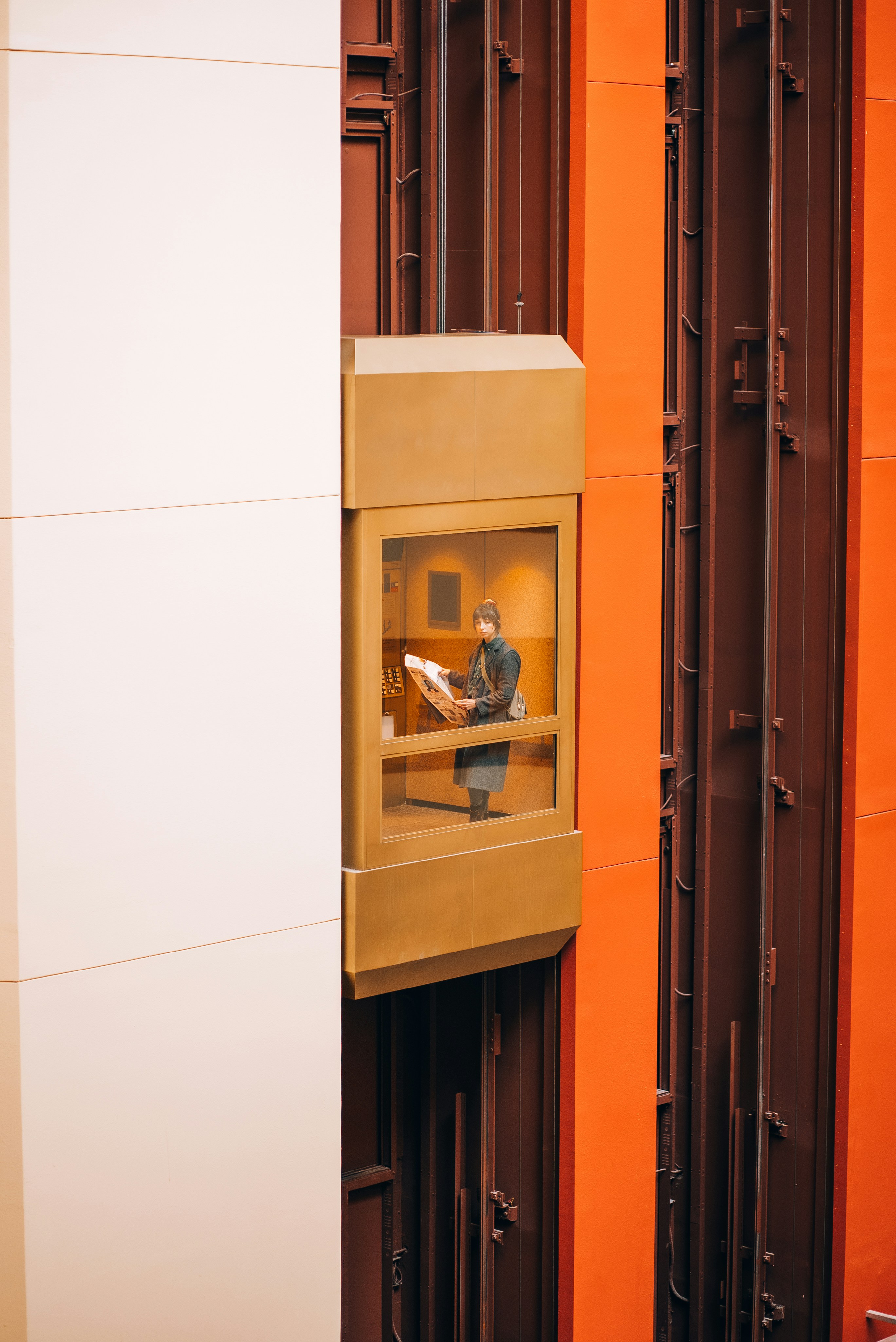 Person framed within an orange-and-white architectural facade