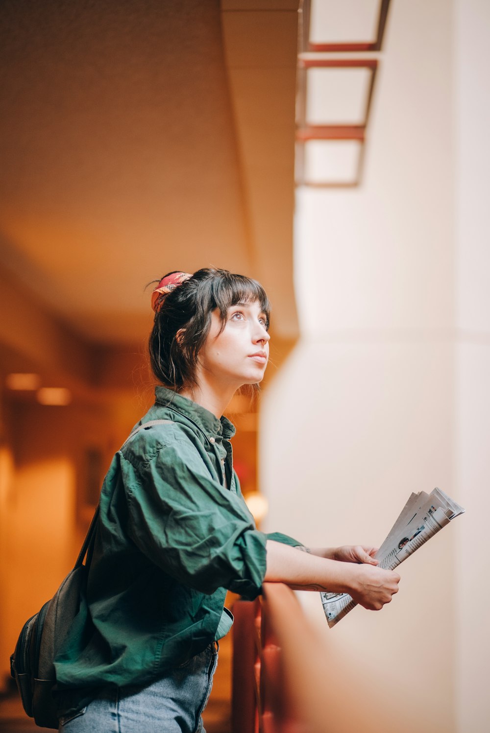 a woman standing next to a wall with a book in her hand