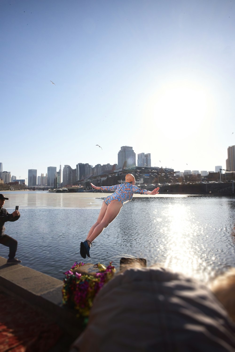 a woman jumping into the water from a pier