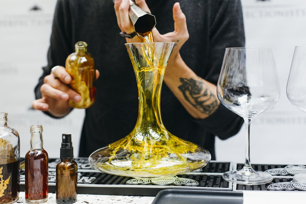 a man pouring olive oil into a glass vase